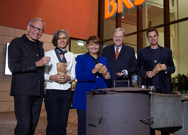 Fünf Personen, darunter Frau Herta Stockbauer und Herr Nikolaus Juhász, stehen mit heißen Maroni vor der BKS Bank Zentrale.