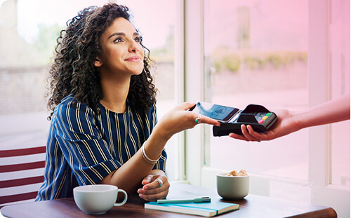 Frau bezahlt im Kaffee mit ihrem Smartphone