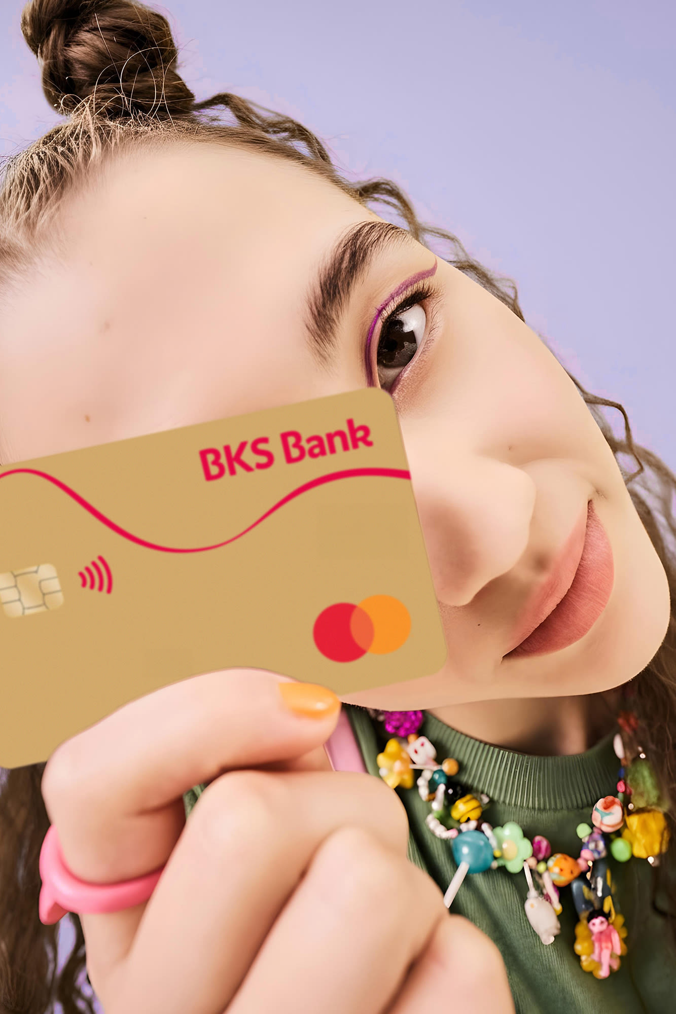 Frau mit BKS-Bank-Karte vor violettem Hintergrund – BKS Mastercard Gold