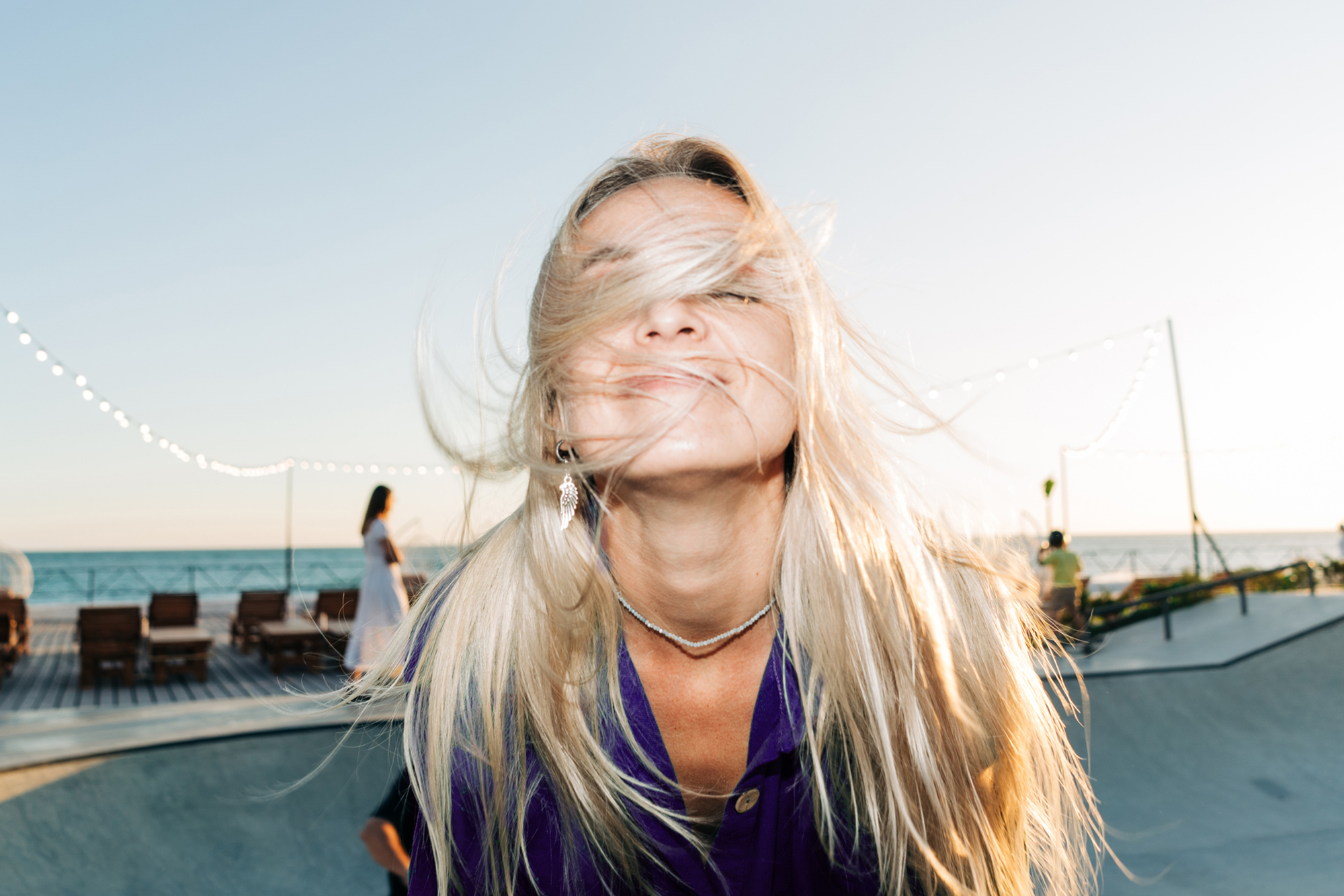 Frau mit wehendem blonden Haar am Meer