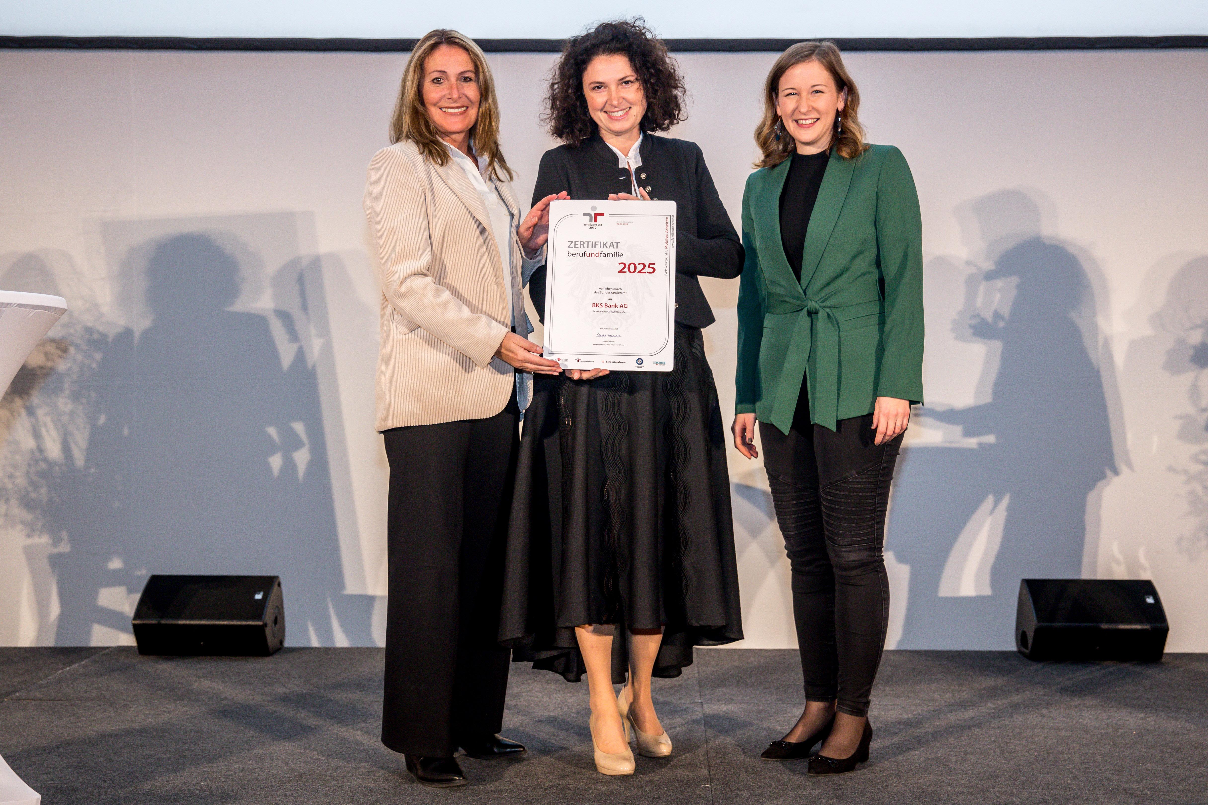 Drei Damen halten das berufundfamilie Zertifikat auf der Bühne - BKS Bank berufundfamilie
