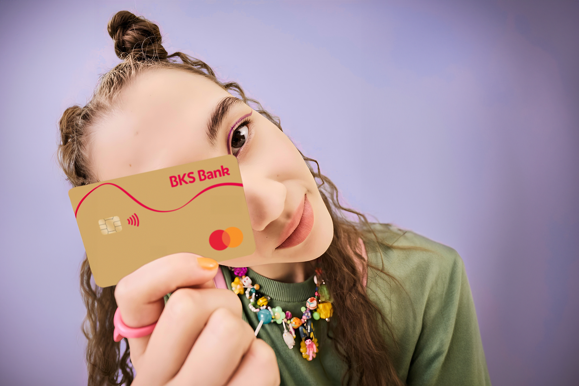 Frau mit BKS-Bank-Karte vor violettem Hintergrund – BKS Mastercard Gold