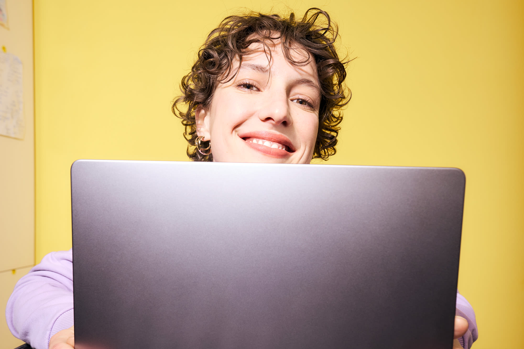 Junge Frau arbeitet am Laptop vor gelbem Hintergrund – flexibel investieren mit Fondssparen bei der BKS Bank.