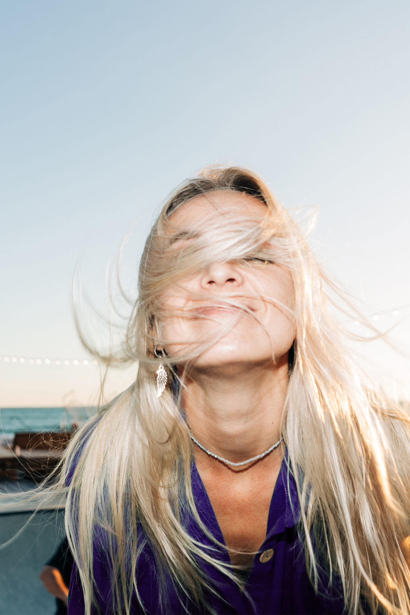 Frau mit wehendem blonden Haar am Meer