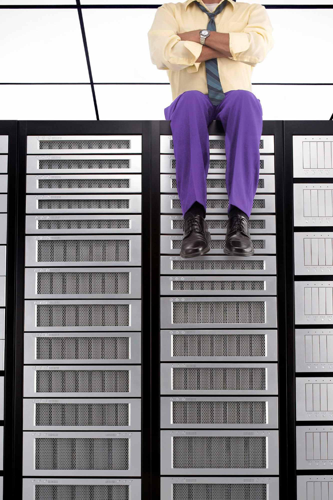 Mann mit Krawatte sitzt auf Serverschrank – Zahlungsabsicherung bei der BKS Bank Mann mit Krawatte sitzt auf Serverschrank – Zahlungsabsicherung bei der BKS Bank