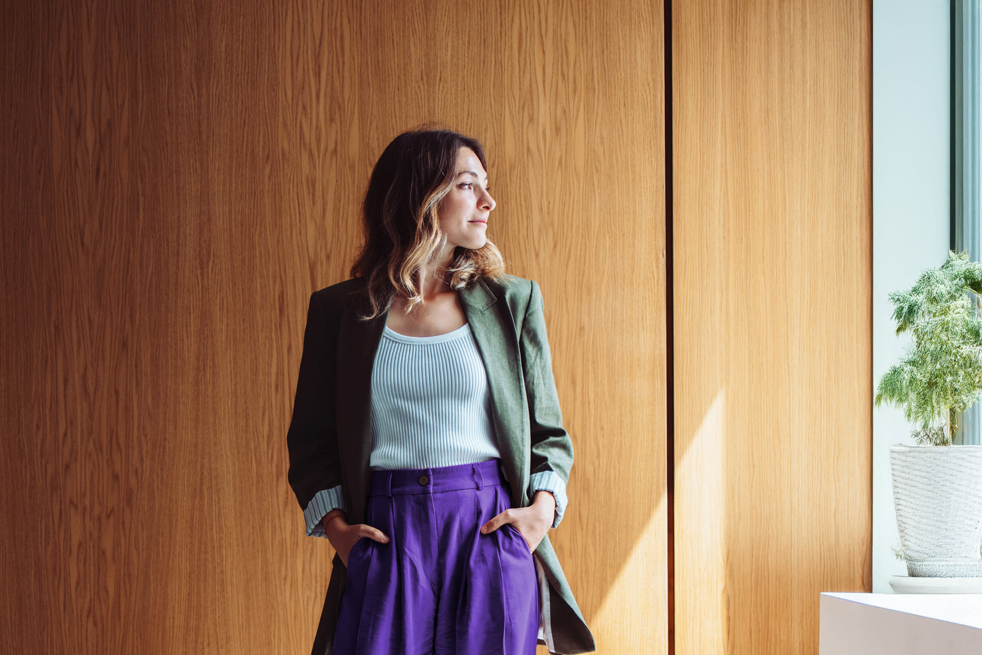 Junge Frau schaut aus Fenster raus – Versichern und Vorsorgen mit der BKS Bank