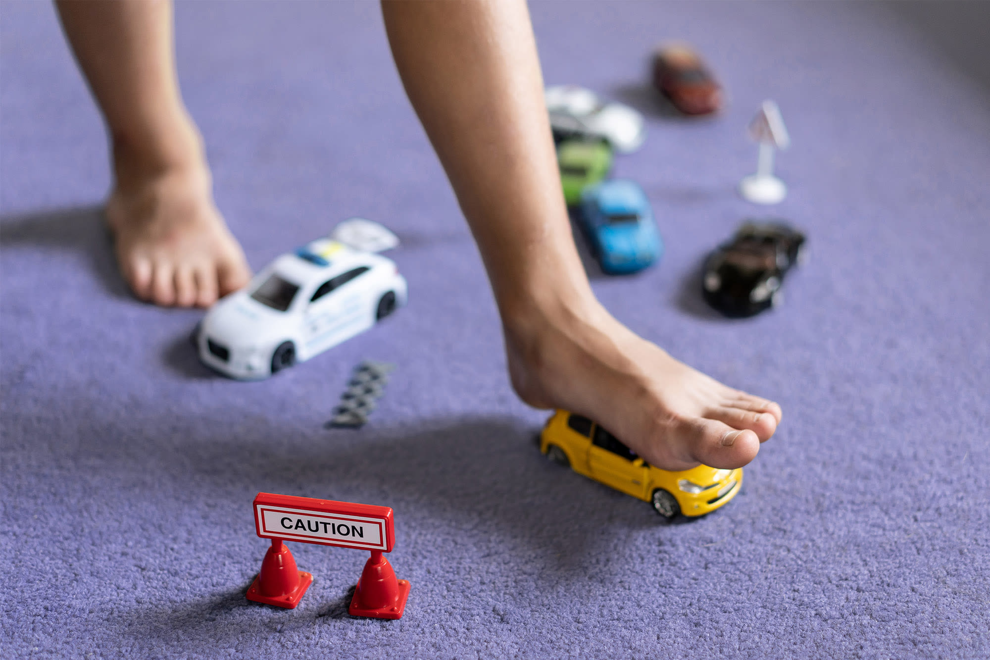 Barfuß auf Spielzeugauto mit Warnschild – BKS All-Risk schützt vor kleinen Unfällen Barfuß auf Spielzeugauto mit Warnschild – BKS All-Risk schützt vor kleinen Unfällen