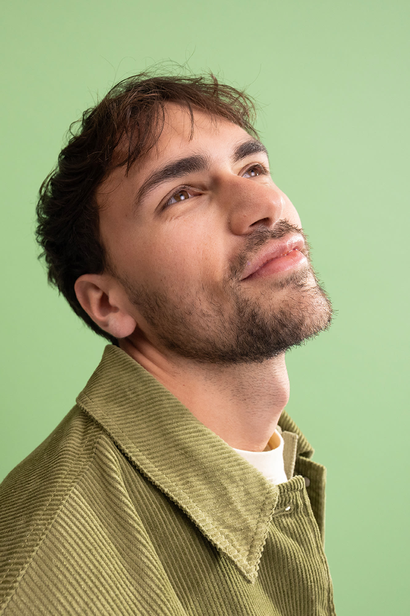 Junger Mann vor grünem Hintergrund mit Blick Richtung Decke.